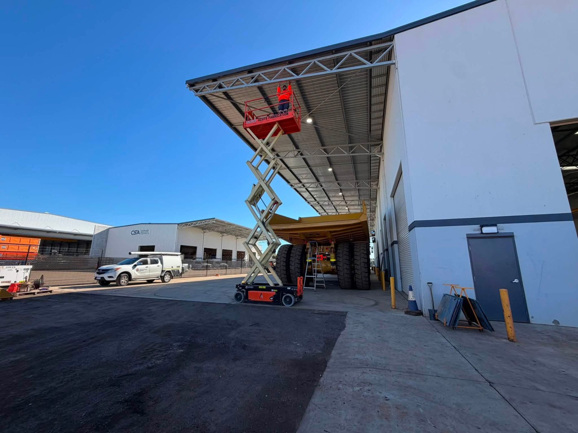 Scissor lift extended under a warehouse canopy