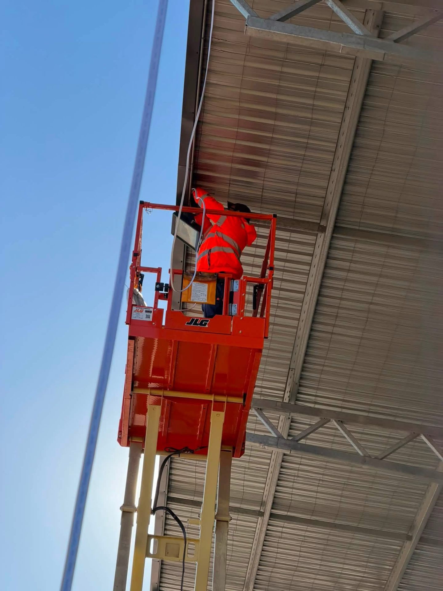 Electrician installing a light from an extended scissor lift