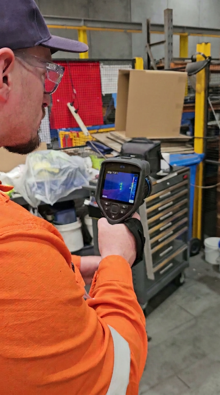 Technician reviewing thermal imagery on a FLIR camera inside a warehouse