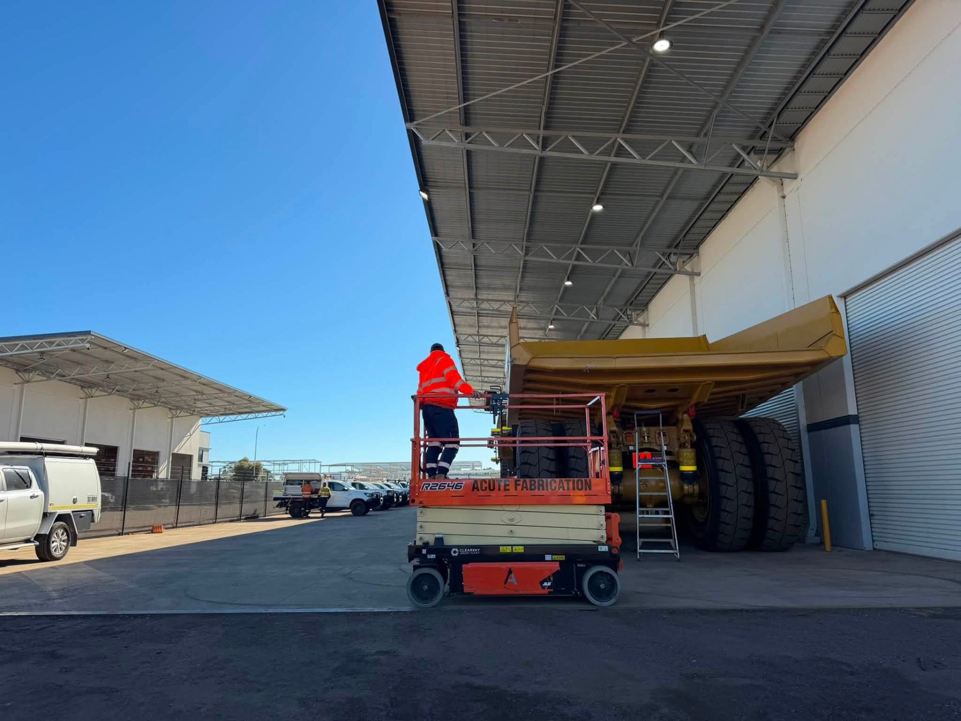 Electrician on a lowered scissor lift beside a haul truck