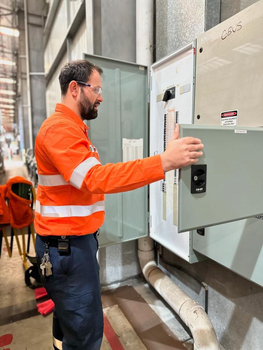 Electrician opening a C-Bus distribution board in a warehouse