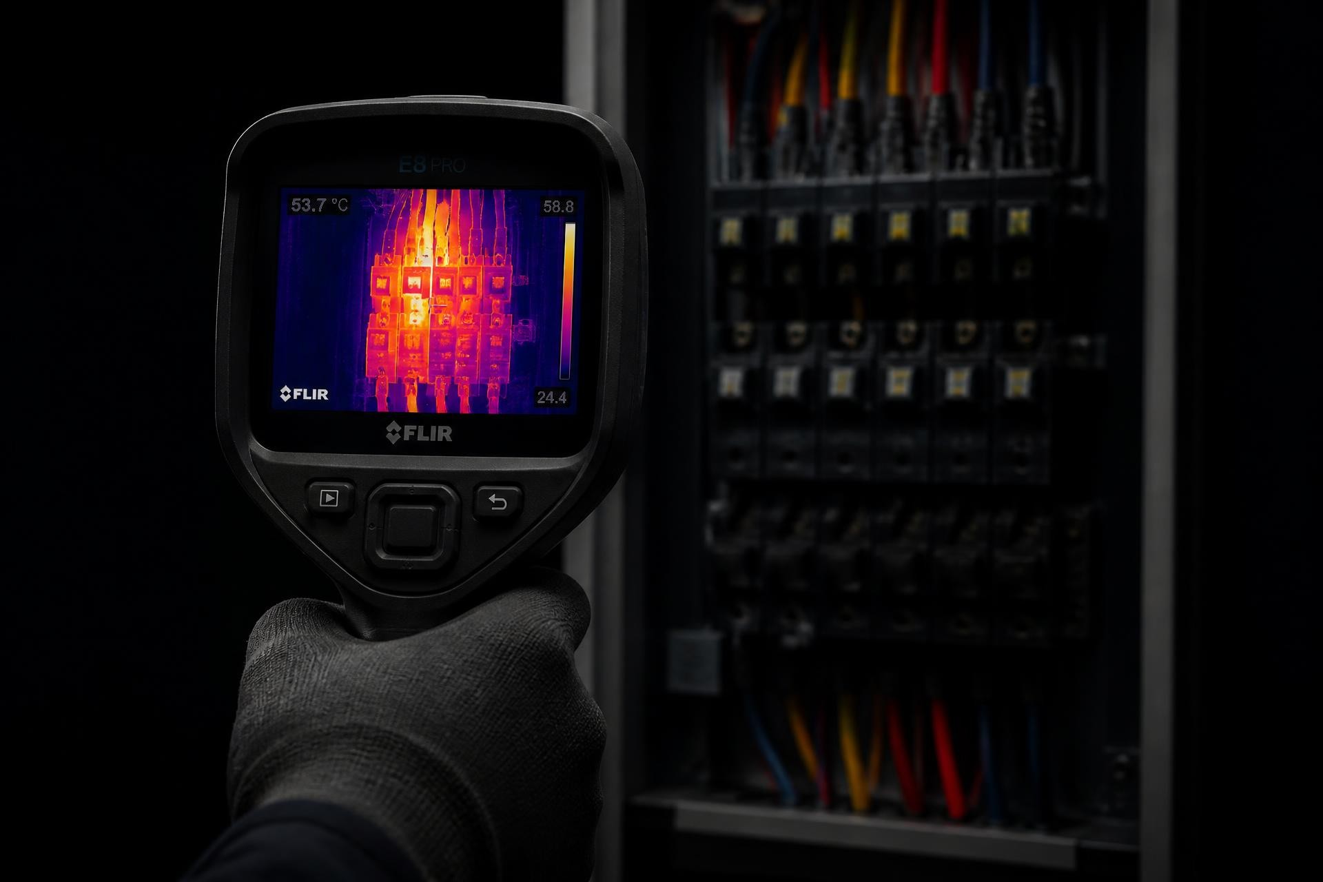 Electrician using a thermal imaging camera on an industrial switchboard